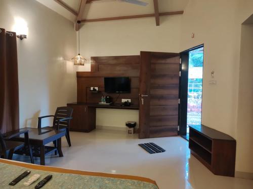 a living room with a table and a tv and a desk at Cocorico Beach Resort in Dapoli