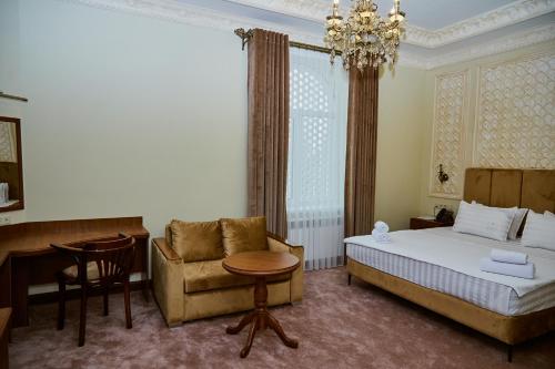 a bedroom with a bed and a chair and a chandelier at Sangzor Boutique Hotel in Samarkand