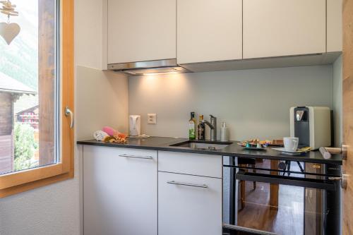 a kitchen with white cabinets and a black counter top at Jolimont Apartments in Zermatt
