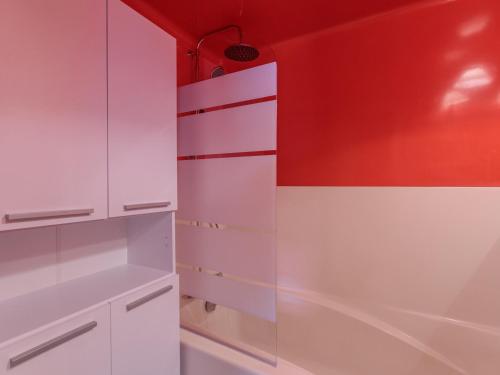 une cuisine avec des placards blancs et un mur rouge dans l'établissement Appartement confortable 2 pièces · 5 pers · Balcon · Centre station - FR-1-346-494, à Arc 1800