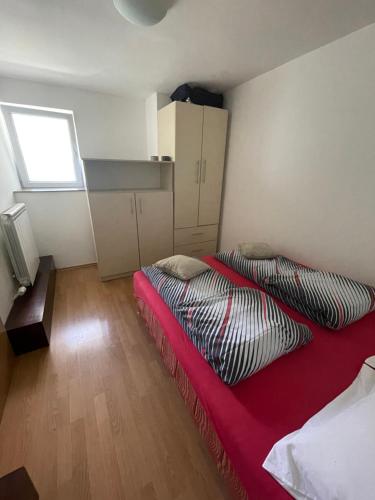 - une chambre avec un lit doté d'une couverture rouge et d'une fenêtre dans l'établissement Kemica, à Sarajevo