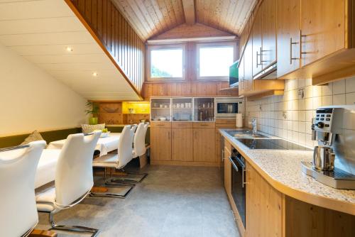 a large kitchen with a long table and white chairs at Gästehaus Fitsch - Ferienwohnung in Silbertal in Silbertal