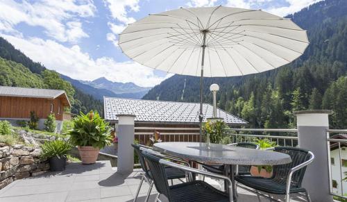 a table and chairs on a balcony with an umbrella at Gästehaus Fitsch - Ferienwohnung in Silbertal in Silbertal