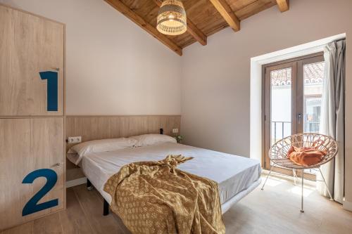 a bedroom with a bed and a chair and a window at Líbere Córdoba Patio Santa Marta in Córdoba