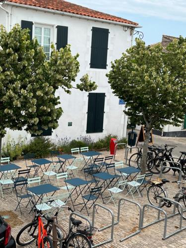 a group of chairs and tables with bikes in front of a building at Chambre d'hôtes Hôte des Portes Île de Ré in Les Portes