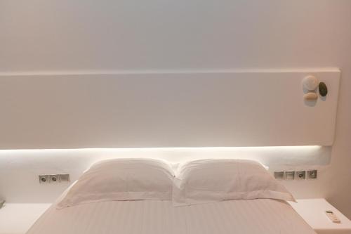 a white bed with white sheets and pillows at Alento Apartments in Tinos Town