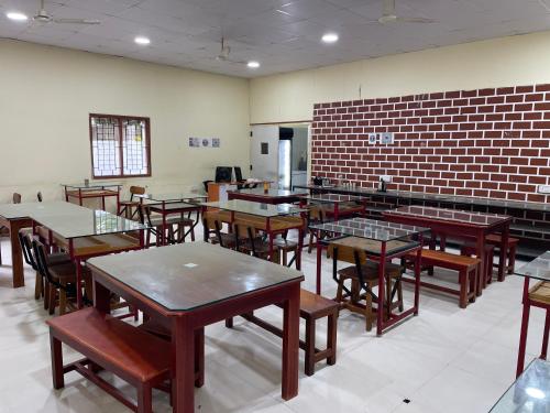 una sala da pranzo con tavoli, sedie e un muro di mattoni di Guesture Serviced Residences, Alta Vista a Bangalore