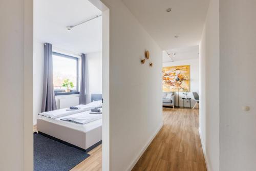 a white bedroom with a bed and a hallway at Glück Auf Appartements Düppelstraße in Oberhausen