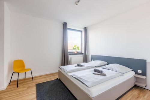 a bedroom with a bed and a yellow chair at Glück Auf Appartements Düppelstraße in Oberhausen