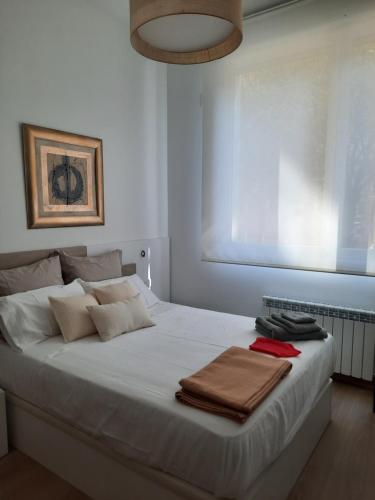 Una cama blanca con toallas en un dormitorio en josemaenea, en Pamplona