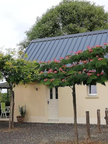 una pequeña casa con techo negro con flores rosas en Gites les 2 Clos au pied du Mont, en Pontorson