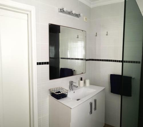 Baño blanco con lavabo y espejo en Los Murillos II, en Las Palmas de Gran Canaria