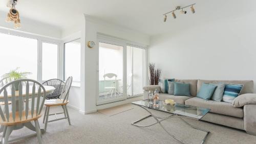uma sala de estar com um sofá e uma mesa em Tides - Beach front apartment in Bracklesham Bay em Chichester
