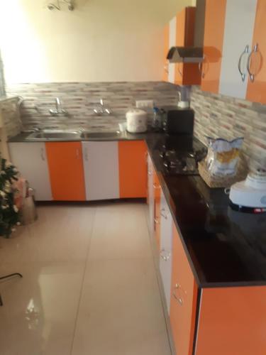 eine Küche mit einer orangefarbenen und weißen Arbeitsplatte in der Unterkunft Nature's Blessing in Chandīgarh
