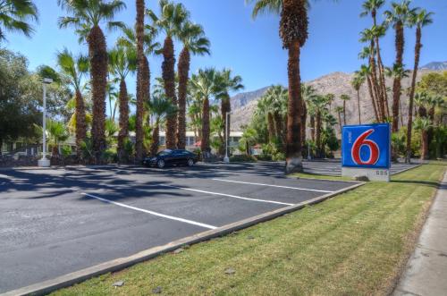 a parking lot with palm trees and a sign with the number six at Motel 6-Palm Springs, CA - East - Palm Canyon in Palm Springs