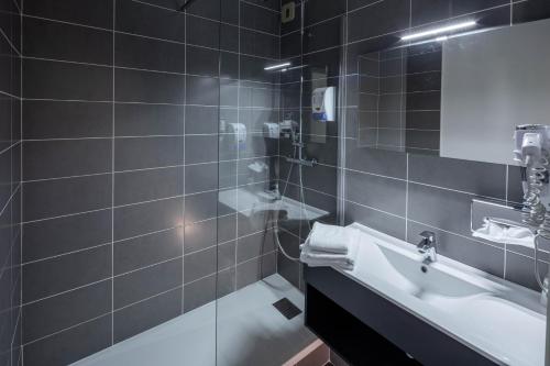 La salle de bains est pourvue d'un lavabo et d'une douche en verre. dans l'établissement Noemys Brive - ex Hôtel Restaurant Le Teinchurier, à Brive-la-Gaillarde