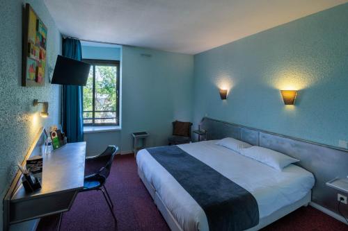 a hotel room with a bed and a desk and a window at Noemys Brive - ex Hôtel Restaurant Le Teinchurier in Brive-la-Gaillarde