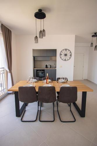 a dining room table with chairs and a clock on the wall at Vertmont Villa in Sveti Stefan