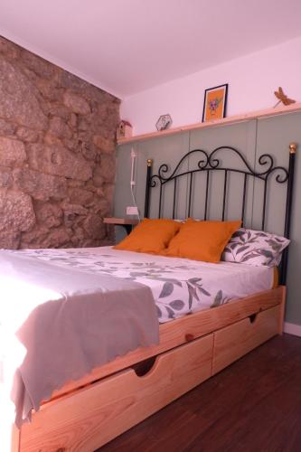 a bed in a room with a stone wall at A casa da Penela in Sas de Penelas