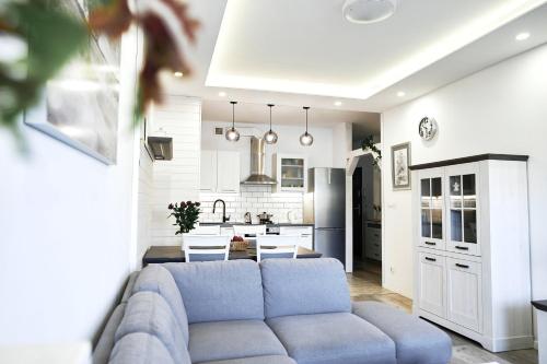 sala de estar y cocina con sofá azul en Komfortowy Apartament z Garażem w Suwałkach - Comfortable Apartment with Garage en Suwałki