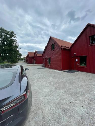 een auto geparkeerd voor een rode schuur bij Rocklunda Village in Västerås