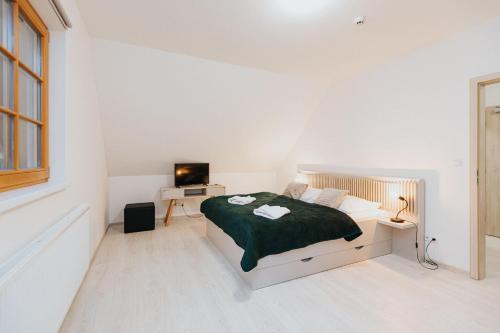 a white bedroom with a bed and a desk at Orava Village in Oravská Lesná