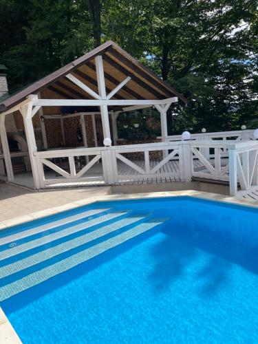 a wooden gazebo with a blue swimming pool at Chalet Mlyn in Migovo