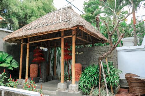 a small pavilion with a roof in a garden at Argya Santi Suite and Villas in Seminyak