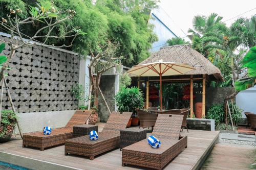 a group of chairs and an umbrella on a wooden deck at Argya Santi Suite and Villas in Seminyak