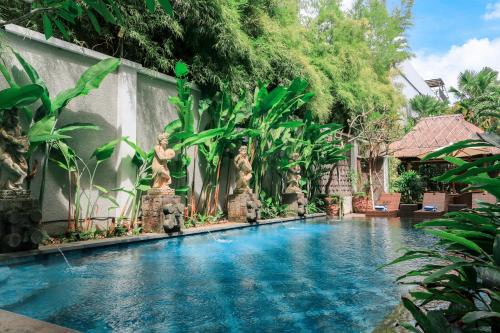 a swimming pool in front of a house with trees at Argya Santi Suite and Villas in Seminyak