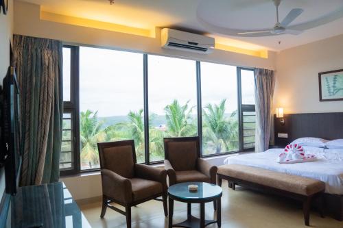 a bedroom with a bed and a large window at Greenleaf The Resort & Spa, Ganpatipule in Ganpatipule