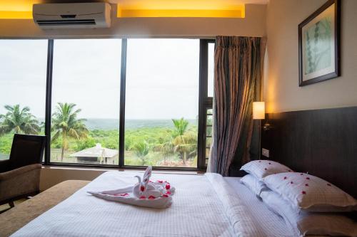 a bedroom with a bed with a large window at Greenleaf The Resort & Spa, Ganpatipule in Ganpatipule