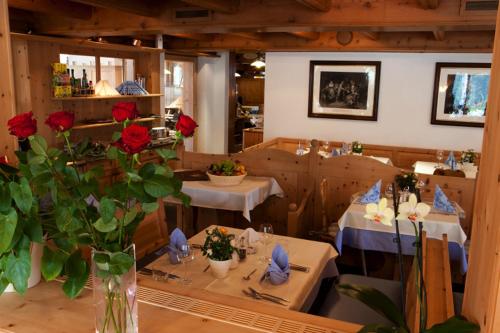 a restaurant with two tables and a vase with red roses at Hotel Astras in Scuol