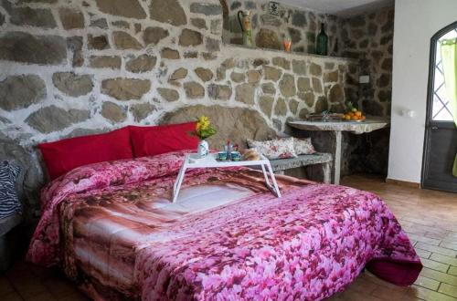 a bedroom with a pink bed with a stone wall at Villa Jewels ,casa vacanza in Gaggi
