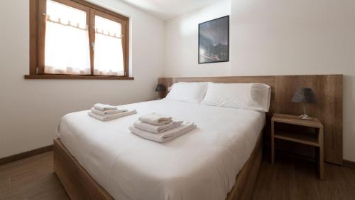 a bedroom with a white bed with towels on it at Italianway - Ciuk 11 in Bormio