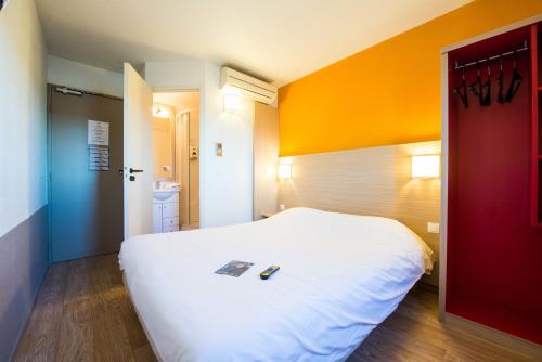 
a bedroom with a bed and a dresser at Hôtel Kennedy Parc des Expositions in Tarbes
