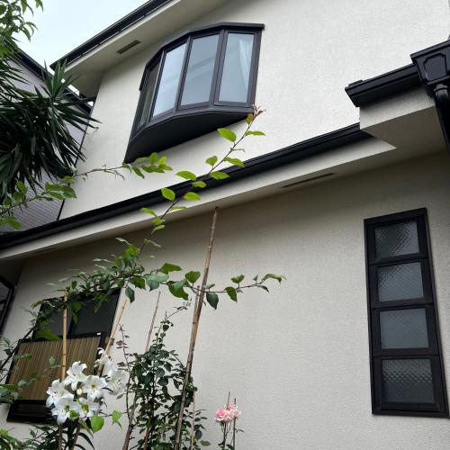 a white house with black windows and plants at japan house shinkoiwa guest house in Tokyo