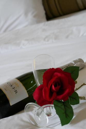 a red rose and a bottle of wine on a bed at Hotel Rodovoli in Konitsa