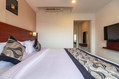 a bedroom with a large white bed with a flat screen tv at Zip By Spree Hotels Mangala Towers Thrissur in Trichūr