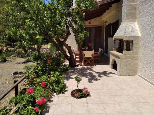 a patio with a fireplace and a table and flowers at Villa Kalliopi in Lápithos