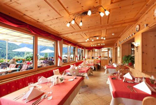 a restaurant with red tables and chairs and windows at Hotel Astras in Scuol