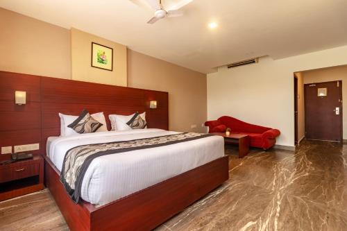 a bedroom with a large bed and a red chair at Zip By Spree Hotels Mangala Towers Thrissur in Trichūr