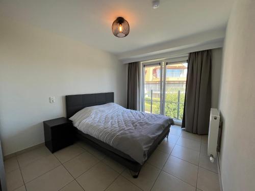 a bedroom with a bed and a large window at Botticelli in Koksijde