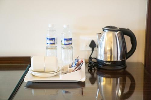 a coffee maker sitting on a table with a tea pot and water bottles at Greenleaf The Resort & Spa, Ganpatipule in Ganpatipule