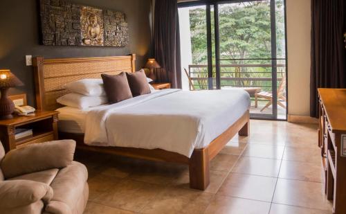 a bedroom with a large bed and a balcony at Hotel Ladera in Boquete