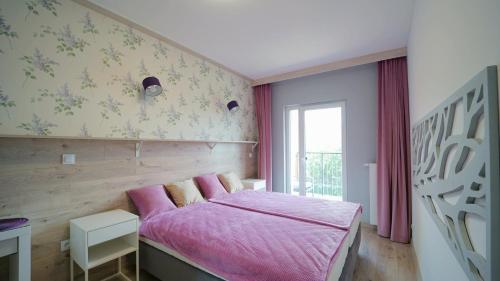 a bedroom with a pink bed and a window at Apartamenty EverySky - Kilińskiego 2 in Świeradów-Zdrój