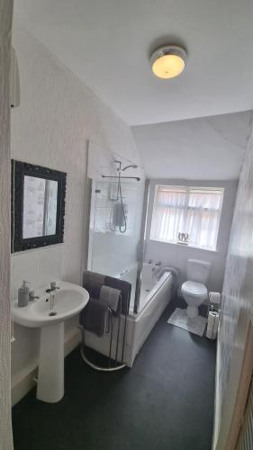 a bathroom with a tub and a toilet and a sink at Cruden Villa - Second Floor Apartment in Scarborough