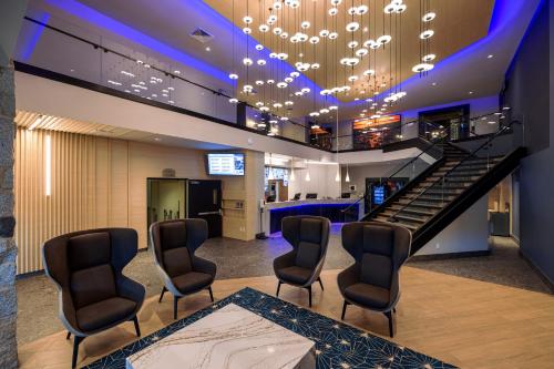a salon with chairs and a staircase and a bar at Hôtel Universel, Centre de congrès Rivière-du-Loup in Rivière-du-Loup