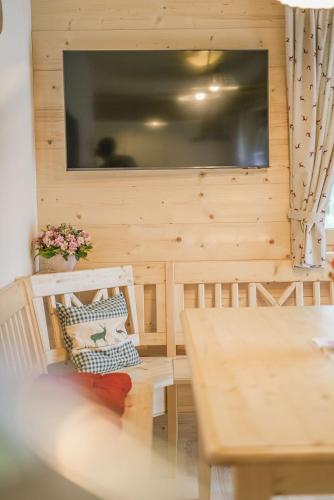 a room with a wooden wall with a table and a television at Forsthaus Toplitzsee in Gössl