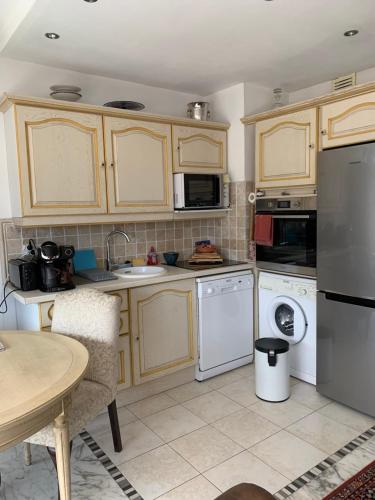 - une cuisine avec des placards en bois et des appareils blancs dans l'établissement Résidence Le Président - Forville, à Cannes